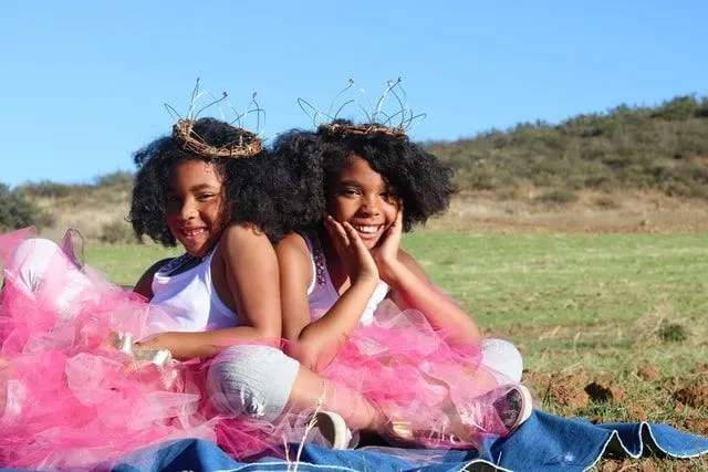 Two girls wearing crowns sitting in the field