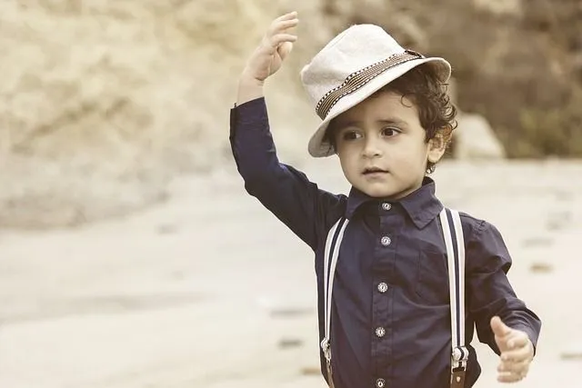 A little boy wearing blue shirt and jute hat