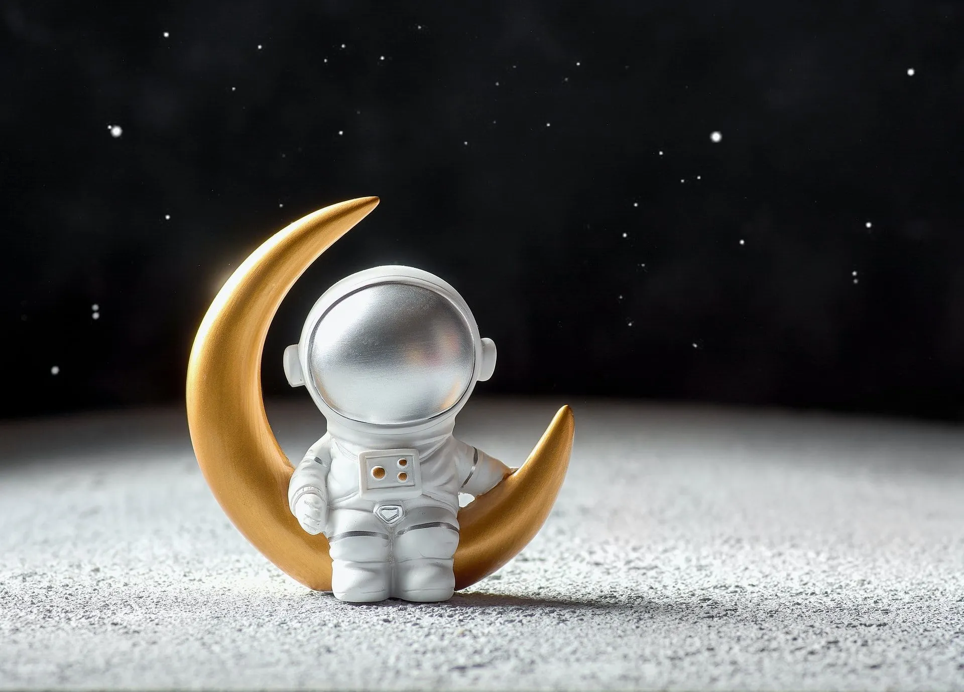 Miniature astronaut and golden moon with stars in the sky