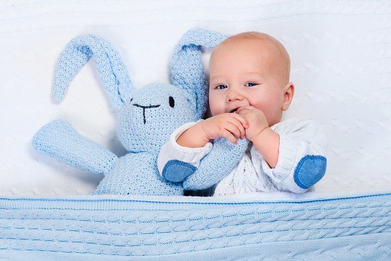 Newborn baby Damien wearing a warm knitted jacket playing with toy bunny - Nicknames