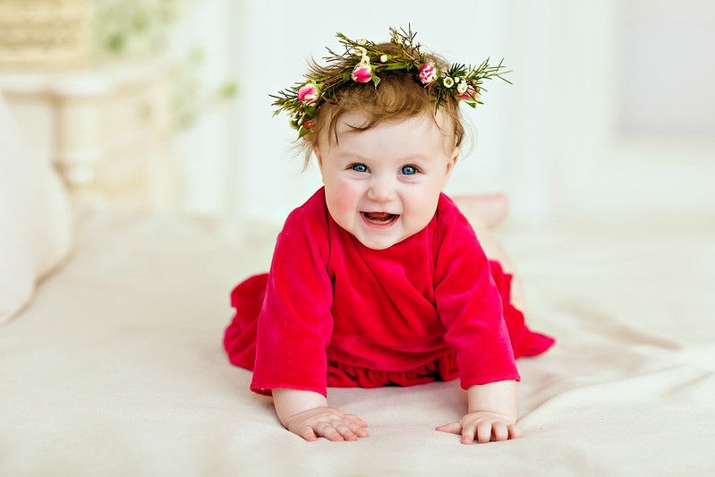 Smiling baby girl Maya wearing red dress and flower tiara - Nicknames.