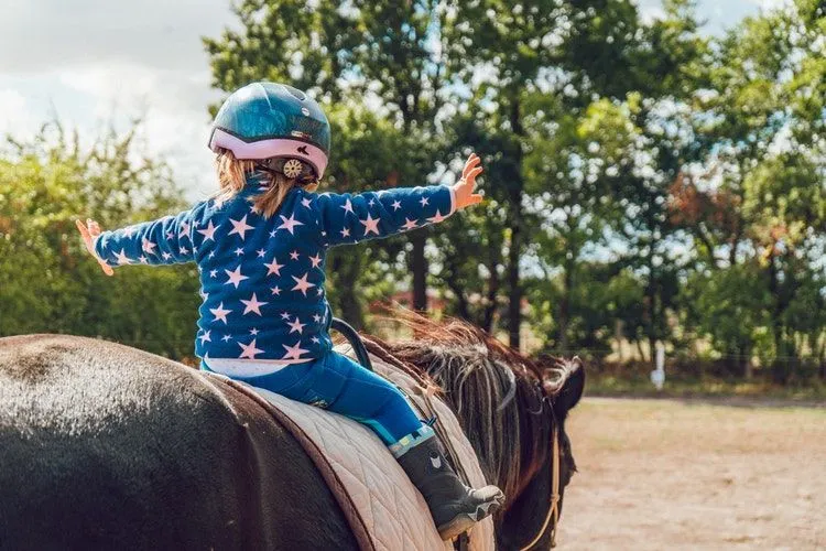 A brave little girl sitting on horse