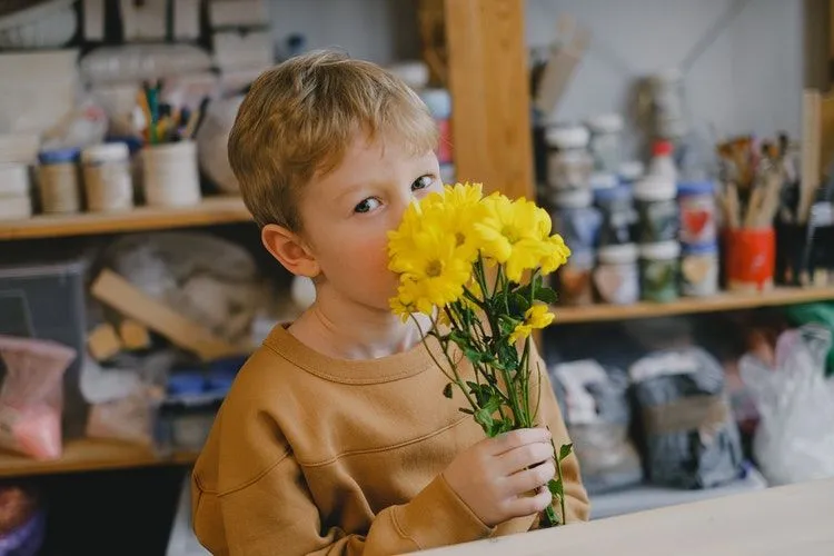 A boy smelling yellow flowers in his hands