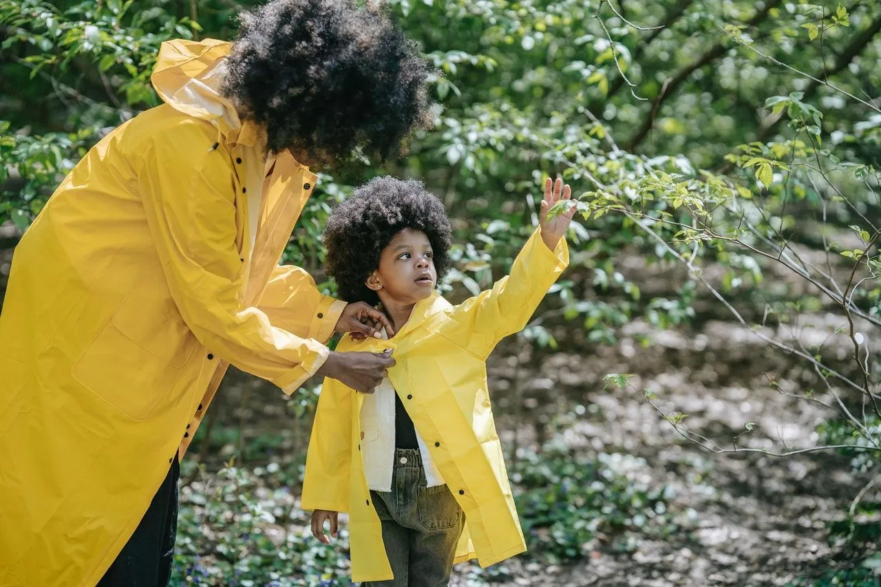 A little girl and mother wearing yellow jackets in a forest