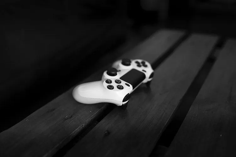 A white video game controller on wooden bench