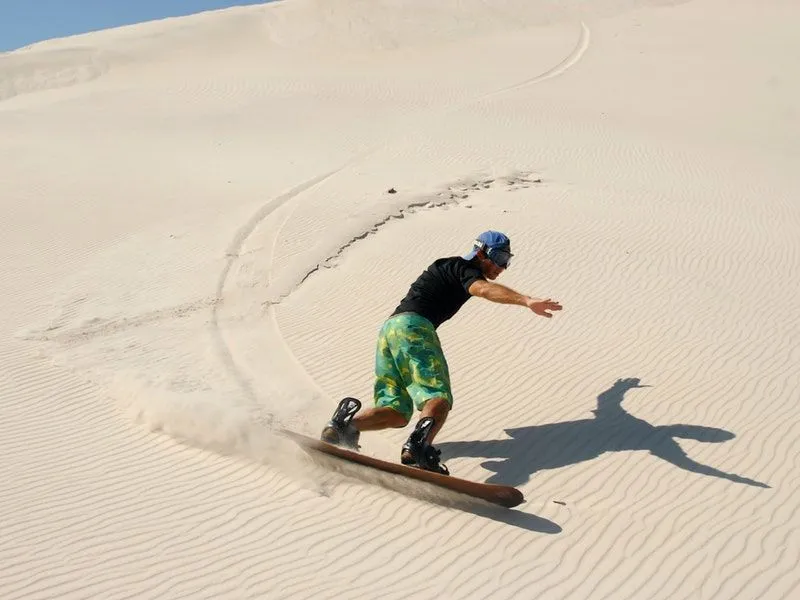 A man sandboarding in desert