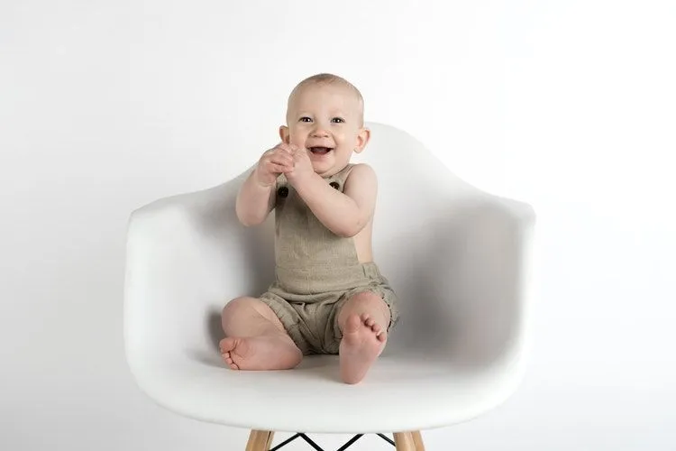 A happy baby boy sitting on a white chair