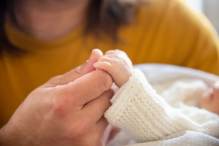 Mother holding the tiny hand of her newborn baby