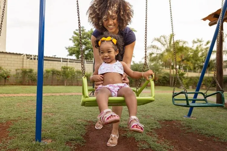 Mother helping her daughter swing 