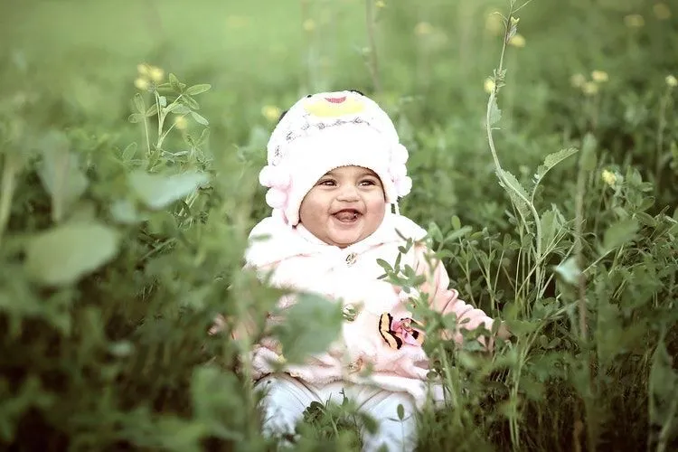 A baby girl sitting in a field
