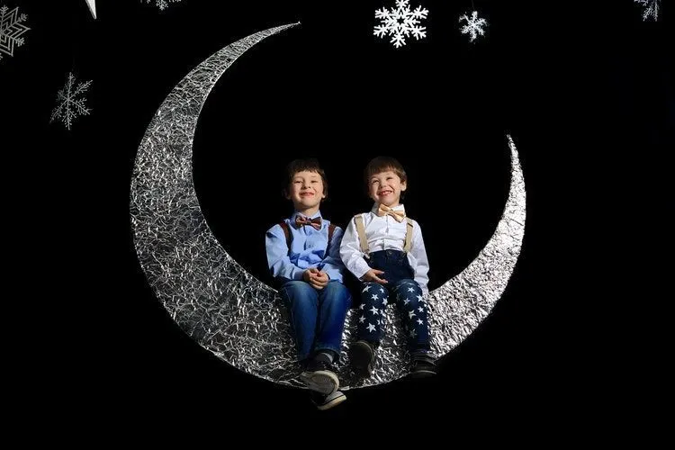 Two boys sitting on silver crescent moon