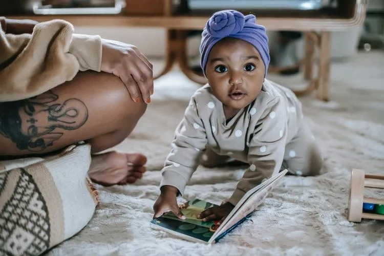 A baby girl crawling with a book