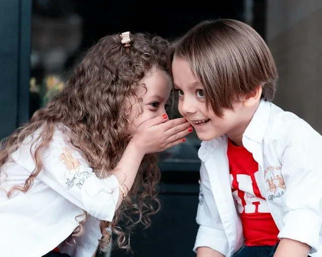 Little girl whispering in a boy's ears
