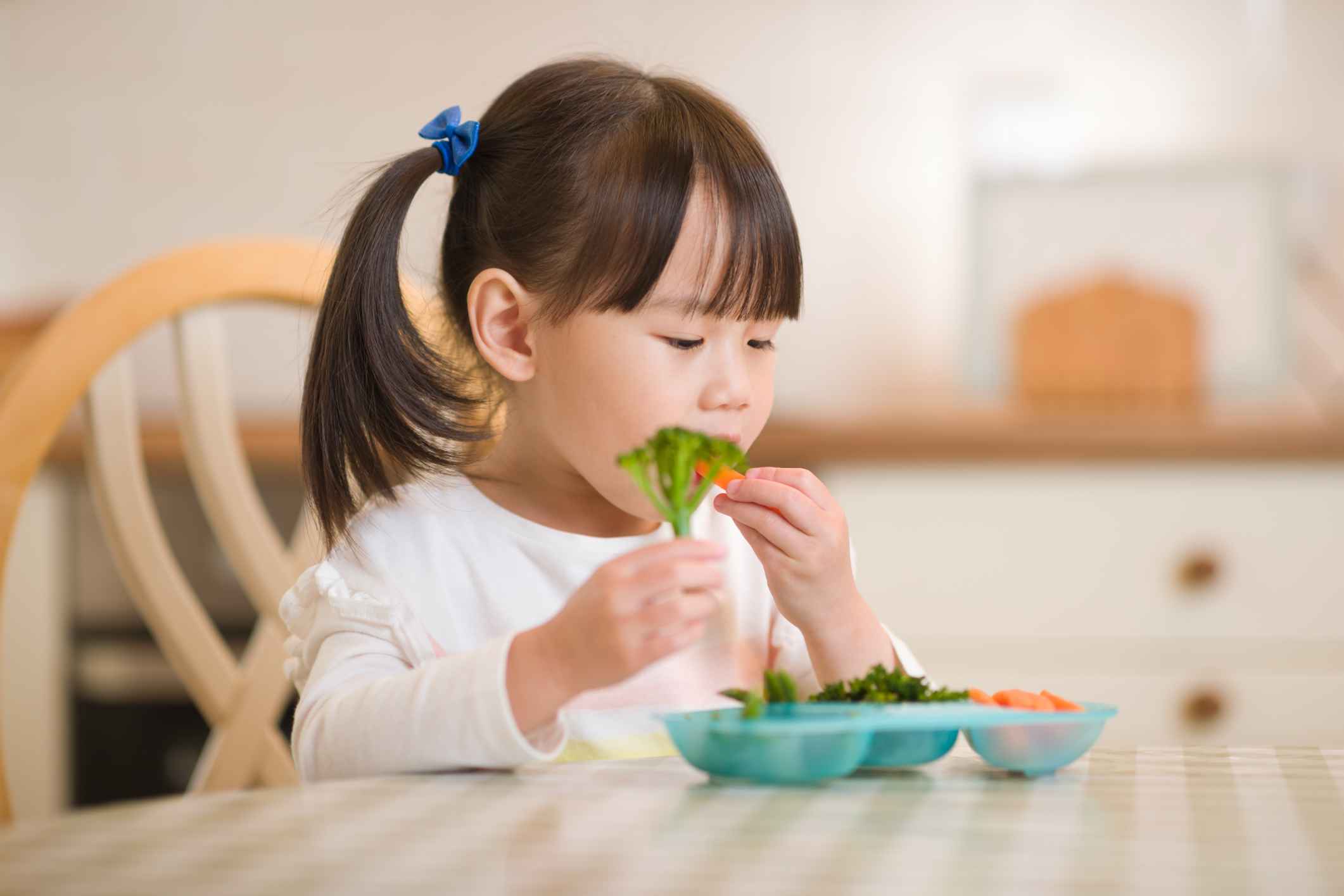 Young girl eating fresh green vegetales