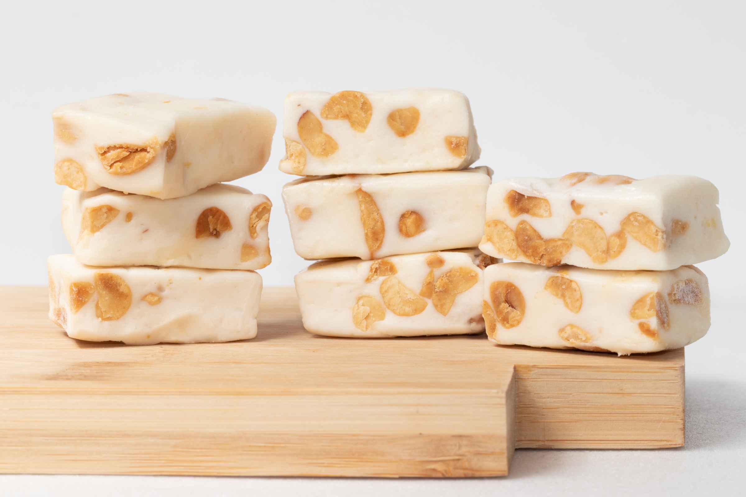A pile of nougat squares on a wooden board