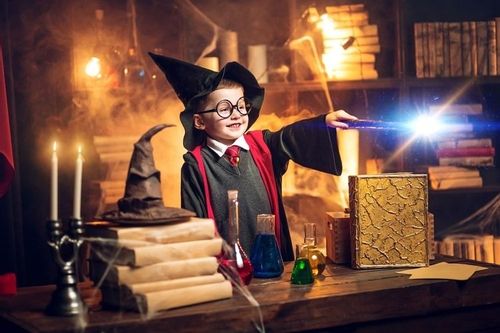 Small wizard in glasses and wizard's hat holding magic wand