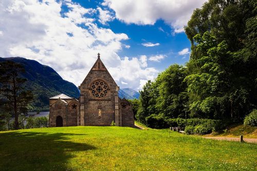 An old architecture church amidst beautiful green landscape and mountains in Scotland 