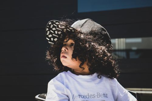 A curly haired kid wearing a black cap