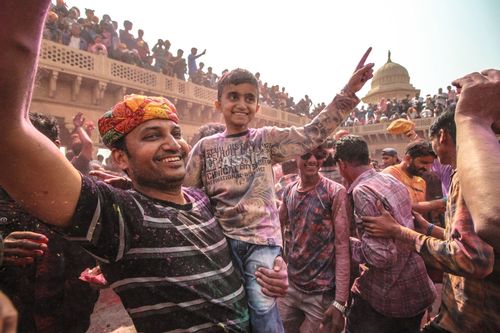 Father with his child is enjoying Holi festival in North India with other people 
