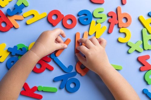 top view of a kid's hands learning alphabet with wooden toys