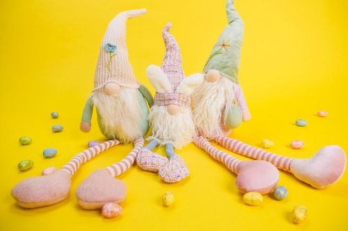 Three stuffed gnome toys on yellow background