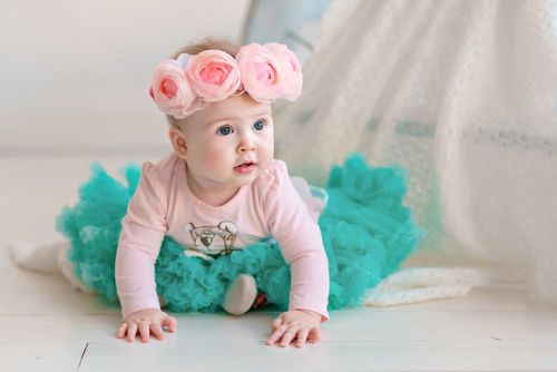 A newborn baby girl wearing rose headband and blue tulle