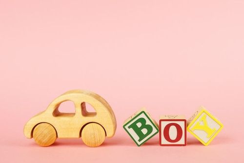 Colored cubes with letters Boy and car toy on a pink background