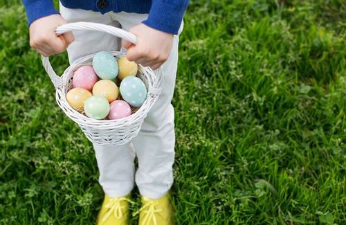 Child holding a basket filled with Easter eggs.
