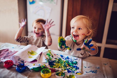 Two young children enjoying finger painting.