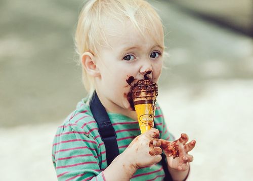 Little boy messily eating ice cream in the summer.