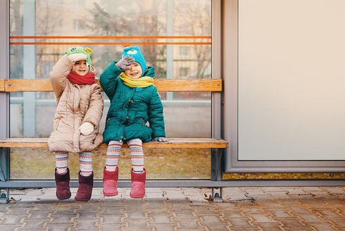 Two girls waiting for the bus in winter