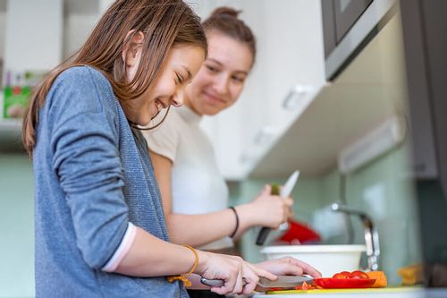 Teen making their own dinner with Mum lending a helping hand.