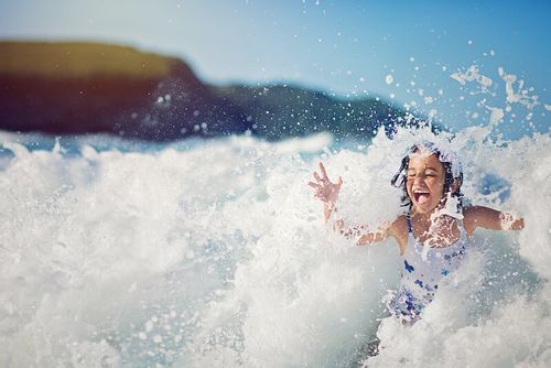 Girl enjoying being splashed in the ocean