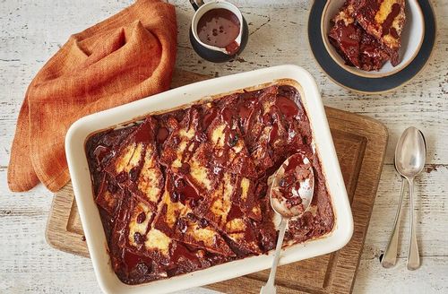 Chocolate bread and butter pudding cooling off in a ceramic dish.