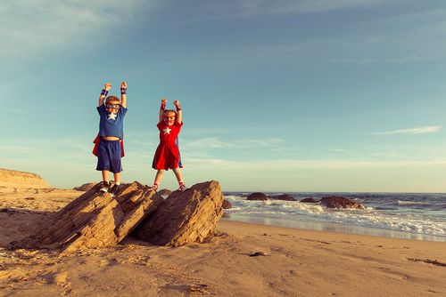 Children dressed as superheroes standing on rocks making rock puns