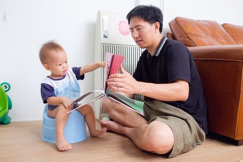 Dad teaching toddler to potty train with potty training books for toddlers.