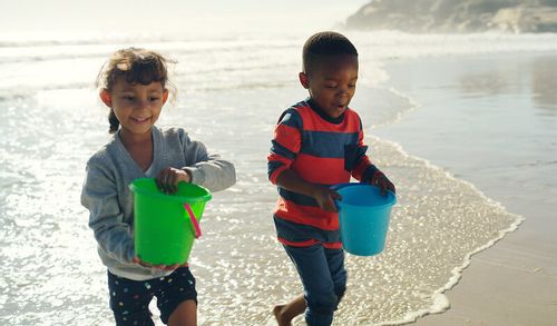 two kids with buckets on an England beach