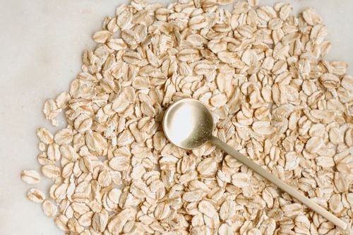 Pile of rolled oats with golden spoon in the middle.