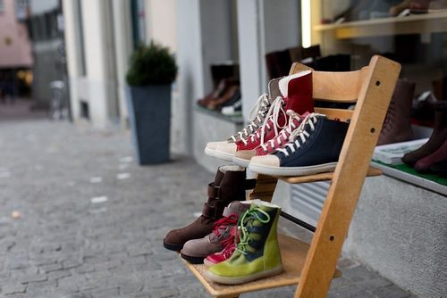 Pairs of shoes on a chair outside a shop window.
