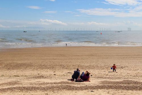 Family sat on the beach on a sunny day at Clacton-on-Sea.