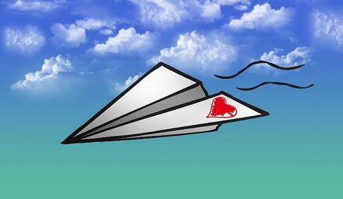 Cartoon origami plane, with a heart drawn on one flap, flying through the sky.