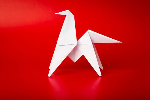 White origami horse against a red background.