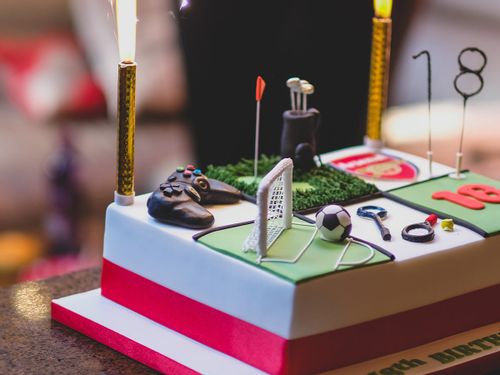 Sports-themed birthday cake with the Arsenal football team logo and a football goal on it.