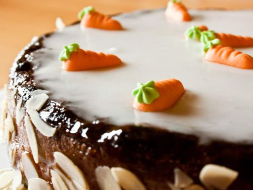 Close up of a cake with white icing and icing carrots on top.