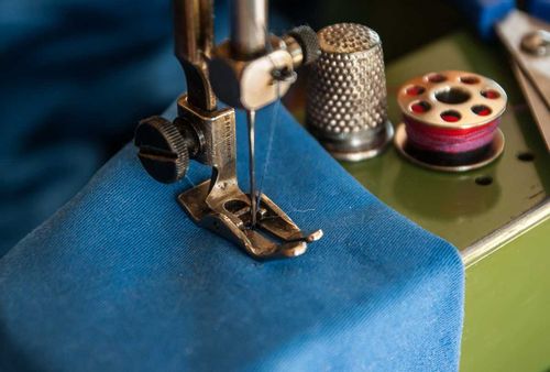 Blue material being stitched in the sewing machine with blue thread.