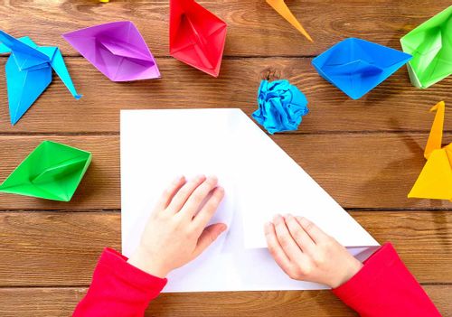 A child's hands folding paper to make origami Pokemon characters.