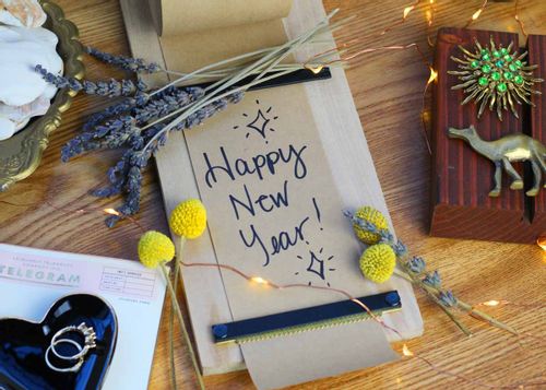 A Happy New Year card with flowers around it lying on the table.
