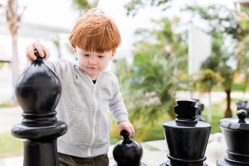 A child playing giant outdoor chess.