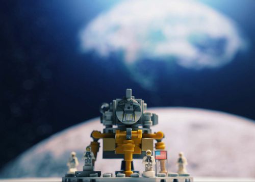 Lego model of a rover with the moon and the Earth in the background.