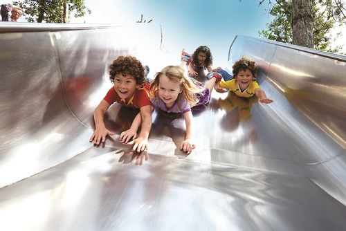 Children enjoying sliding down a slide head-first at Queen Elizabeth Olympic Park.